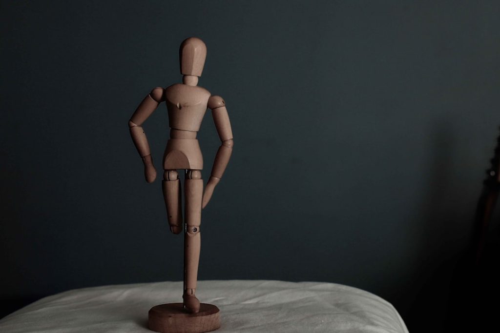 brown wooden human figure on white textile